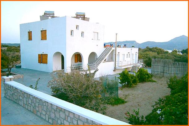 a large white house with a staircase in front of it at Iremia Rooms in Adamantas