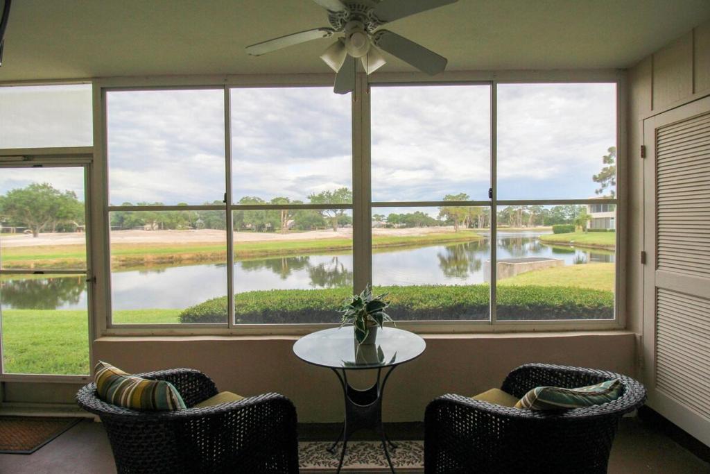 サラソタにあるCharming lakefront condo located in the desirable community of Palm Aireの大きな窓とテーブルと椅子のある部屋