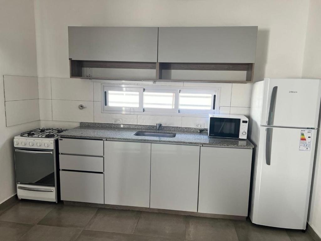 una cucina con mobili bianchi e un frigorifero bianco di Moderno departamento con cochera en el corazón de Resistencia ideal para dos personas a Resistencia