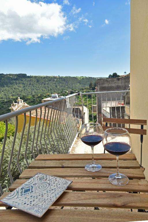 two glasses of wine sitting on a table on a balcony at Sud Casa Vacanze in Ragusa