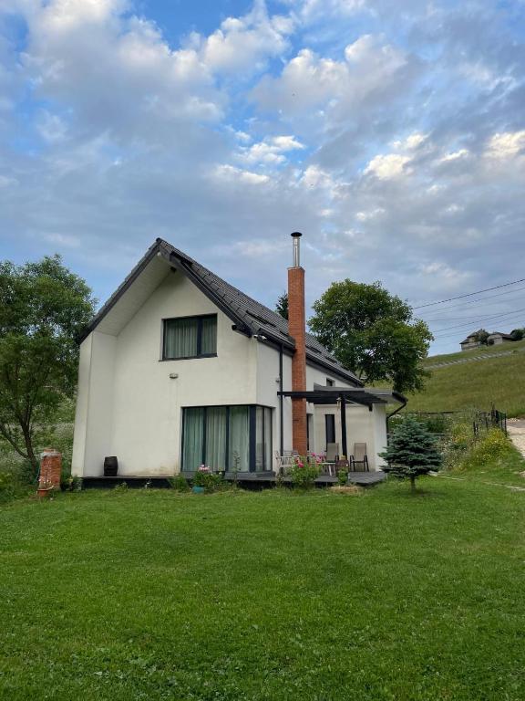 a white house with a chimney on a green field at Odăile Craiului in Şirnea