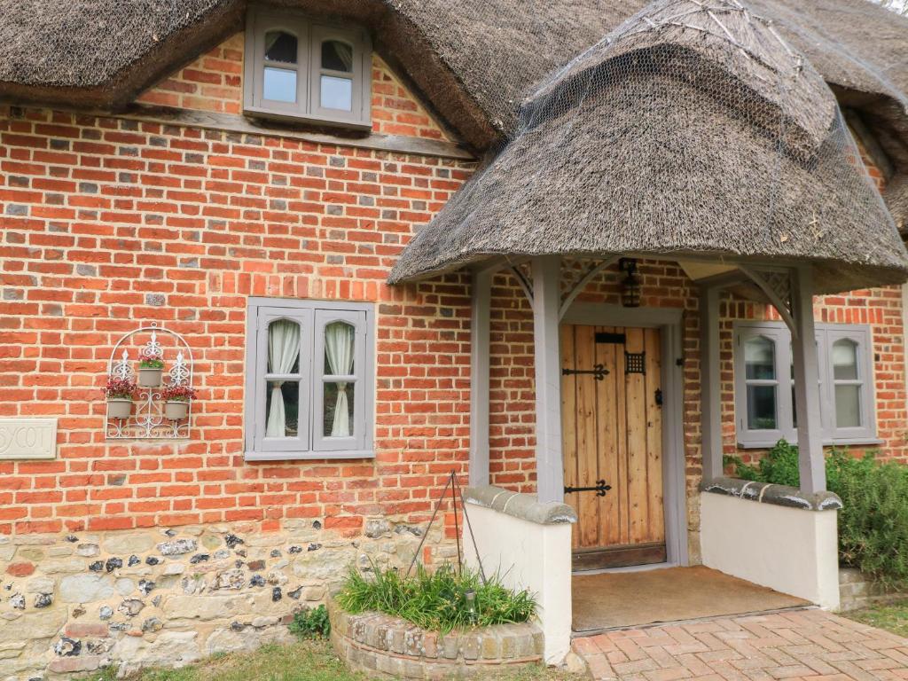 a brick house with a thatch roof at Cosy Cot in Stoford