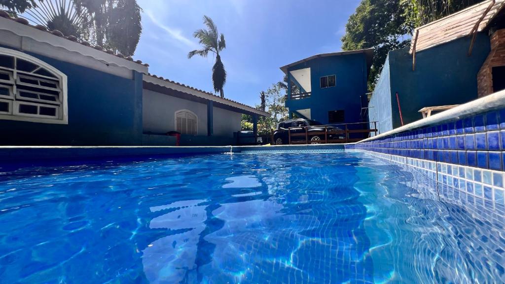a blue swimming pool in front of a house at Suites Oceano in Caraguatatuba