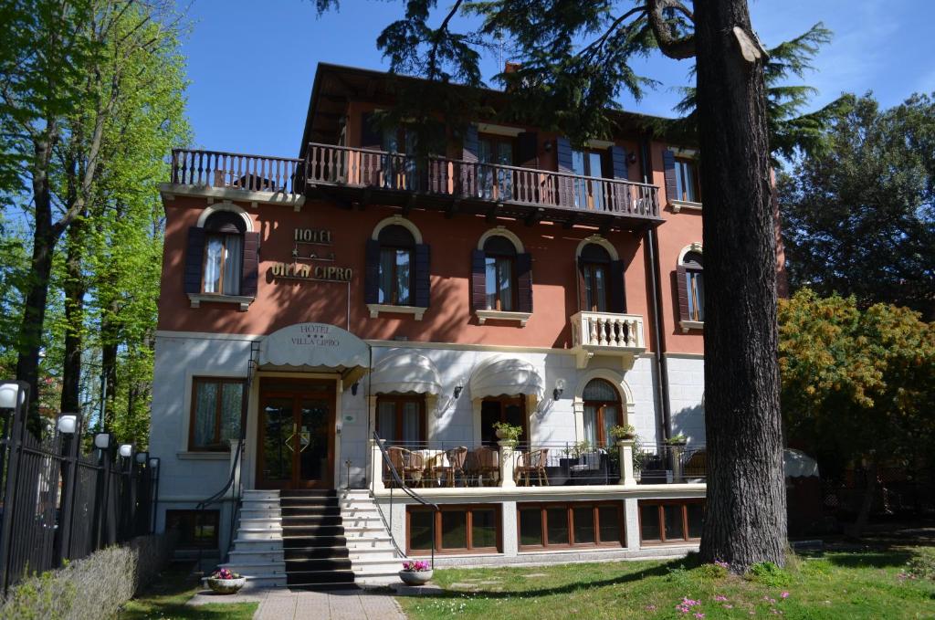 a large red and white house with a tree at Hotel Villa Cipro in Venice-Lido