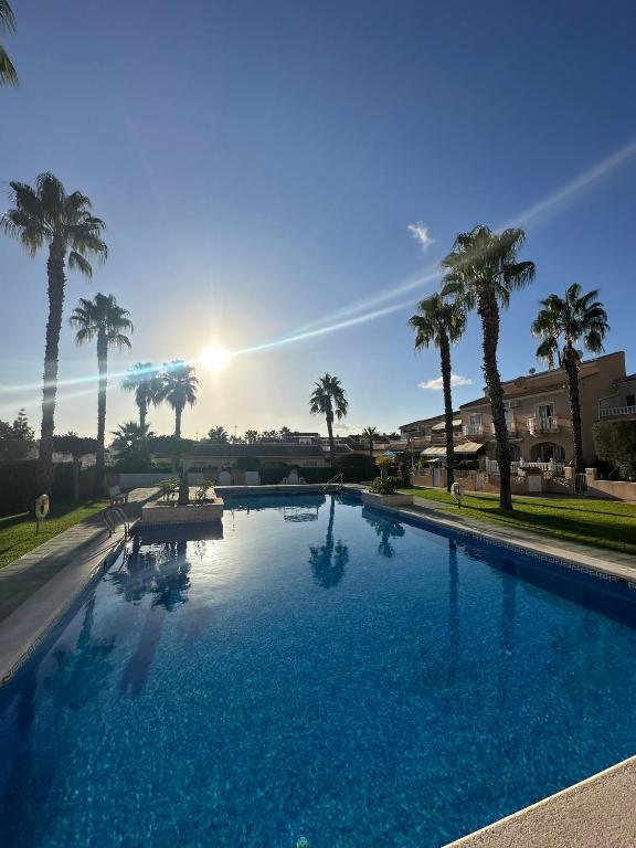 a large swimming pool with palm trees in the background at Luxury Holiday Townhouse with Pool II Casa Macarena 02 in Ciudad Quesada