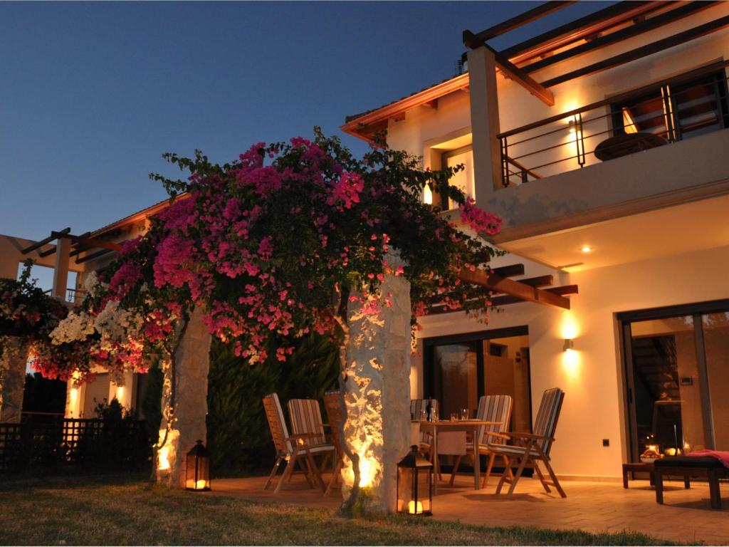 Una casa con un árbol con flores rosas. en Villa Carlos, en Áyios Vasílios