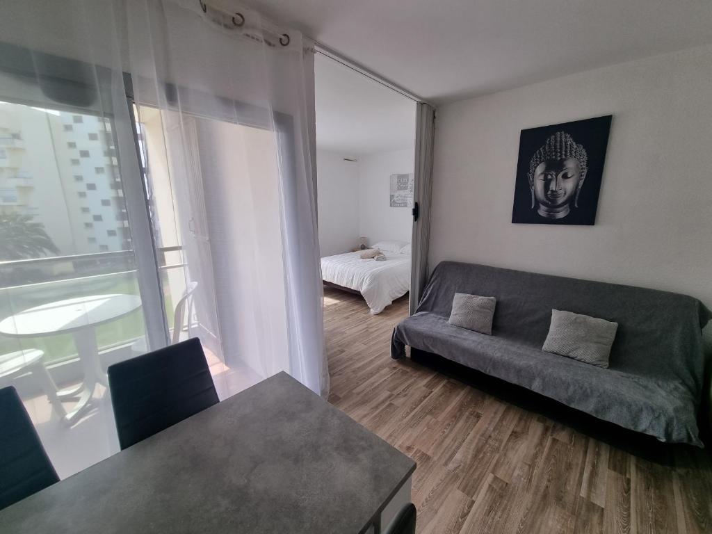 un salon avec un canapé et un lit dans l'établissement Front de mer, Wifi, joli appartement 4 couchages, secteur Lydia Grande plage, au Barcarès