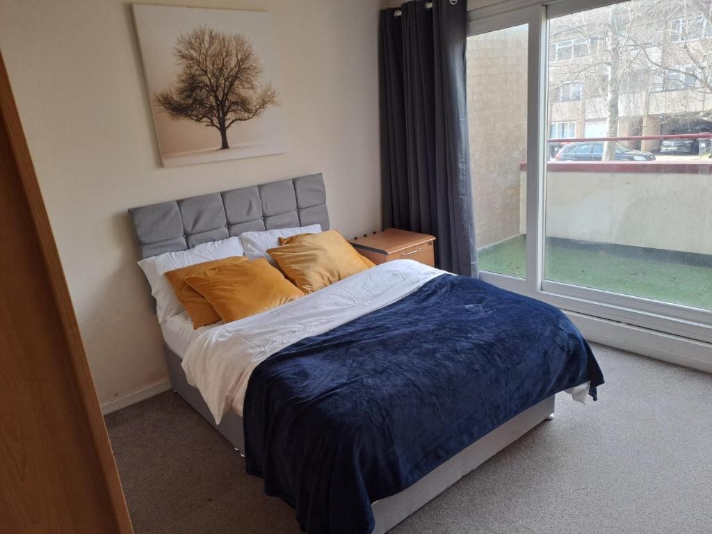 a bed with yellow pillows in a bedroom with a window at House56 in Milton Keynes