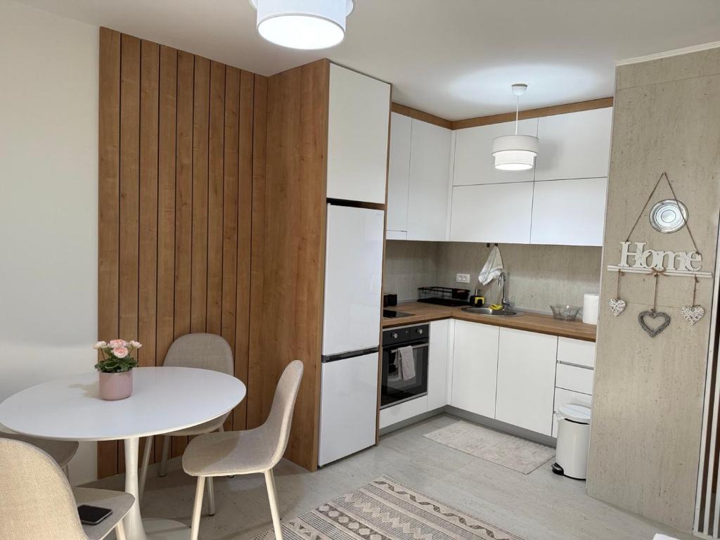 a kitchen with white cabinets and a table with chairs at Sanja apartman in Bar