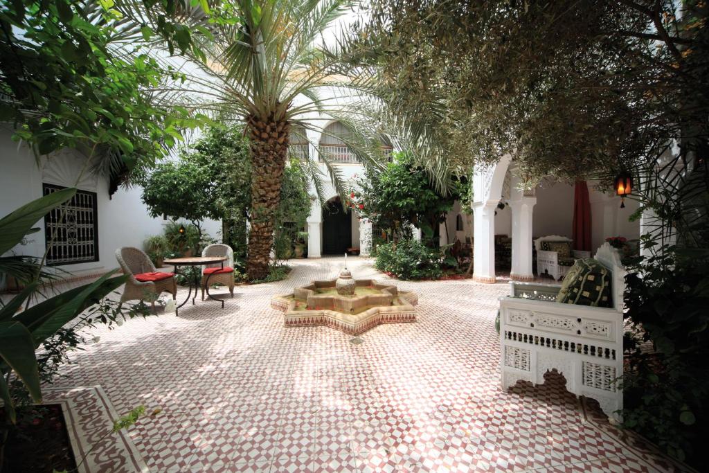 un patio con una fuente en un edificio con árboles en Riad Ifoulki en Marrakech