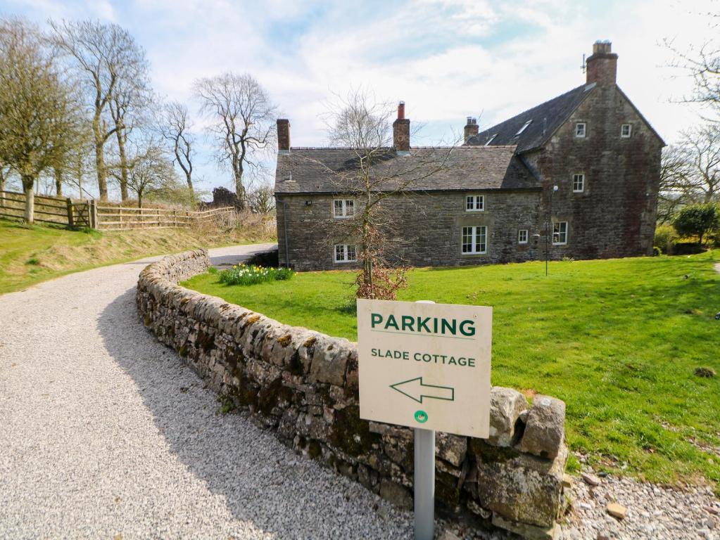 a sign in front of an old house with a building at Slade Cottage in Ashbourne