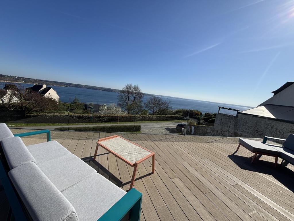 un patio avec un canapé et une table sur une terrasse dans l'établissement Ty Ana Gwen, à Trébeurden