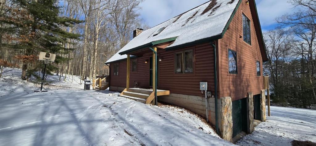 a small wooden house with snow on the ground at Wandering Woods- 3 Bedroom Home with Hot Tub and Firepit in Oakland