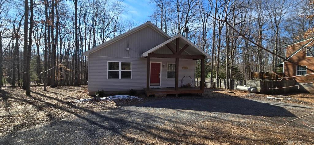 a small white tiny house in the woods at The Hideaway House- 3 bedroom with Hot Tub, Fenced Yard, Lake Access in Swanton