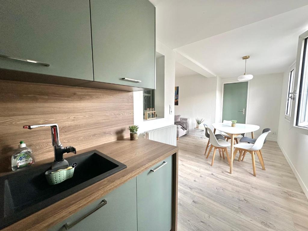 una cucina con un lavello e un tavolo con sedie di Appartement ultra lumineux à Berck-Plage pour 6 personnes a Berck-sur-Mer