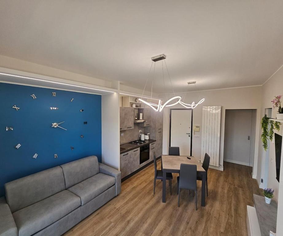 un salon avec un canapé et une table avec une horloge murale dans l'établissement Blu Sky Apartment, à Santa Maria delle Mole