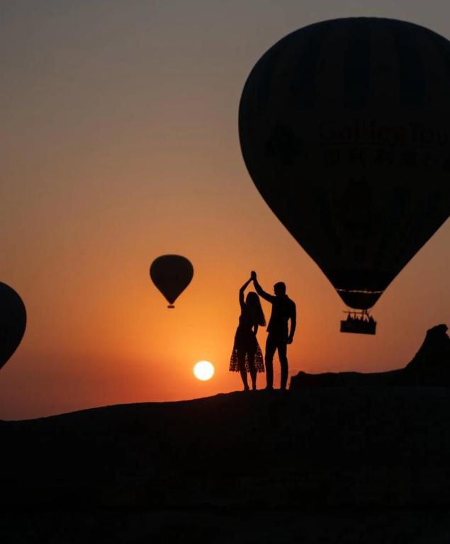 a couple standing on a hill with hot air balloons at Manzara Camping in Pamukkale