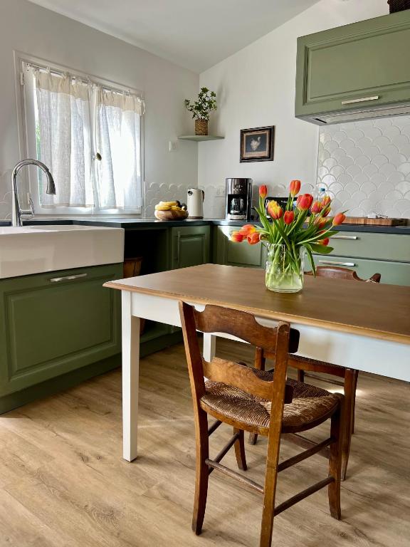 une cuisine avec une table en bois et un vase de fleurs dans l'établissement Le Mûrier, à Lourmarin