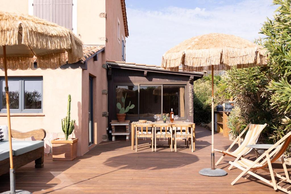 un patio avec une table, des chaises et des parasols dans l'établissement MerSea Beach house at the Sea, Sainte-Maxime, à La Nartelle