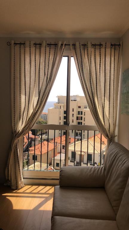 a living room with a couch and a large window at Olivia's Place in Funchal