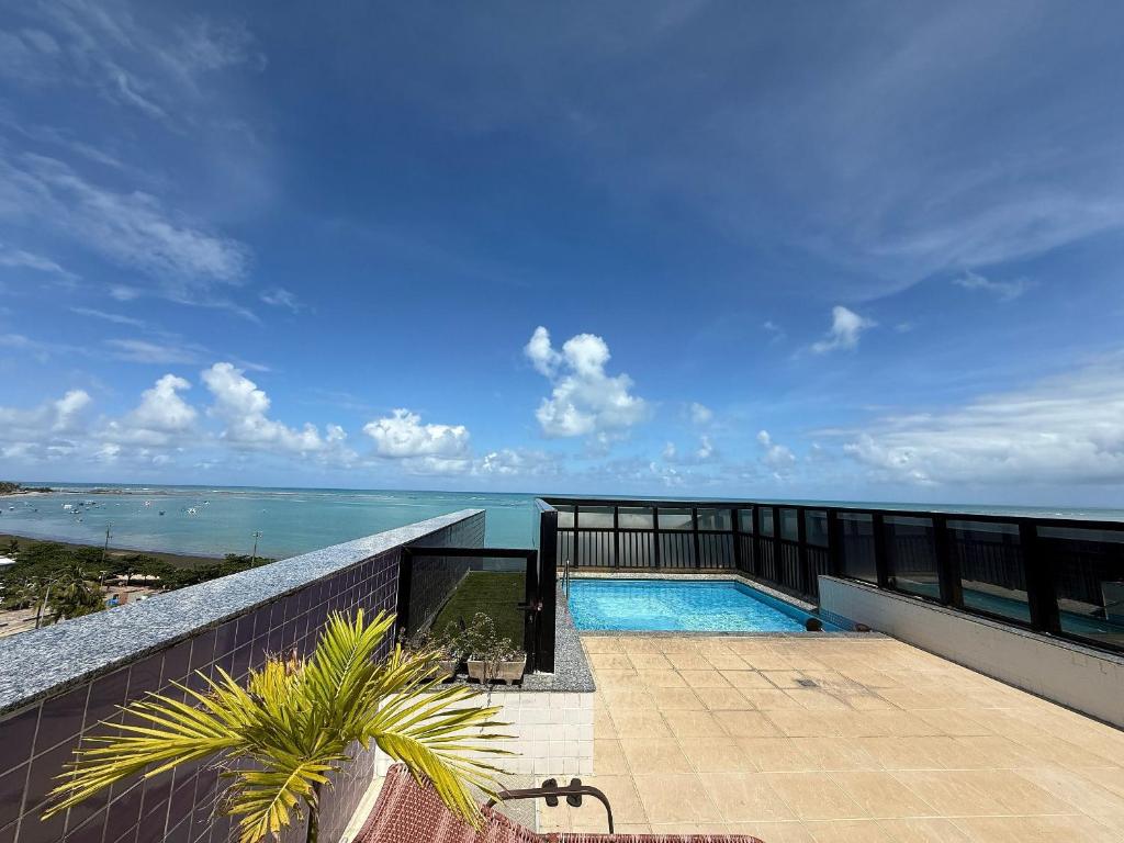 a balcony with a swimming pool and the ocean at Edificio Neo Apto 401 in Maceió