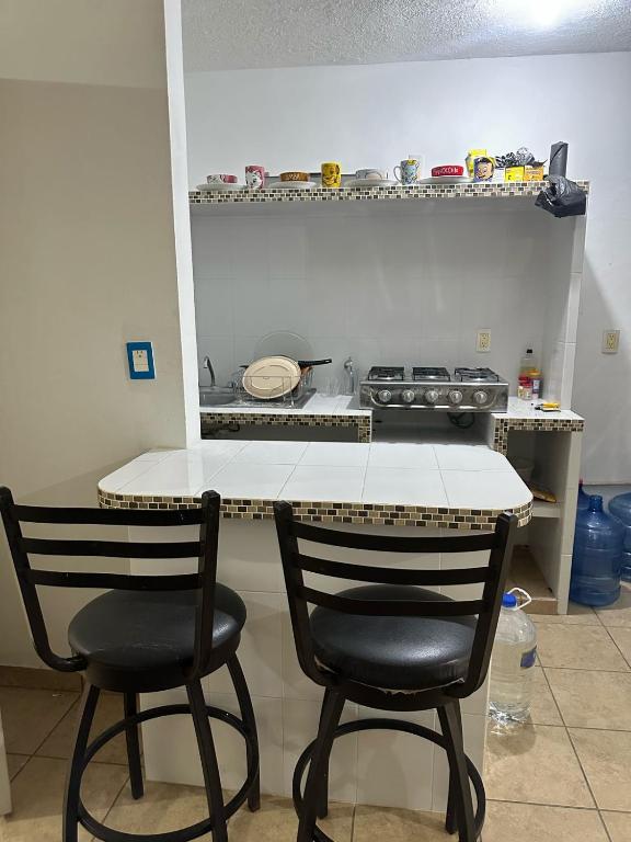a kitchen with two chairs and a table and a stove at Casa en Acapulco los tulipanes in Acapulco