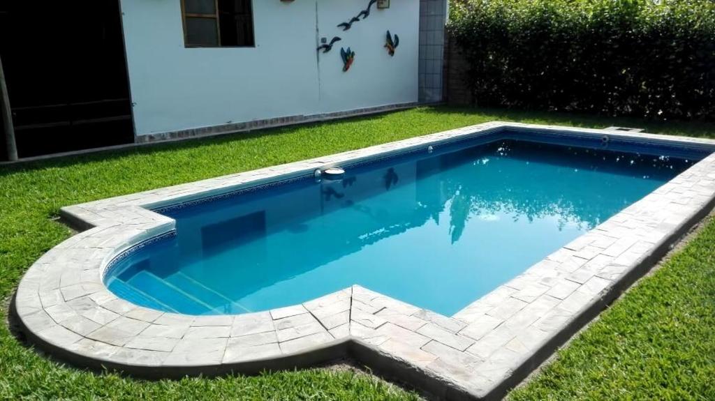a small swimming pool in the grass with a house at Rural retreat pool, 6ppl - 5min beach - SuperHost in Mala