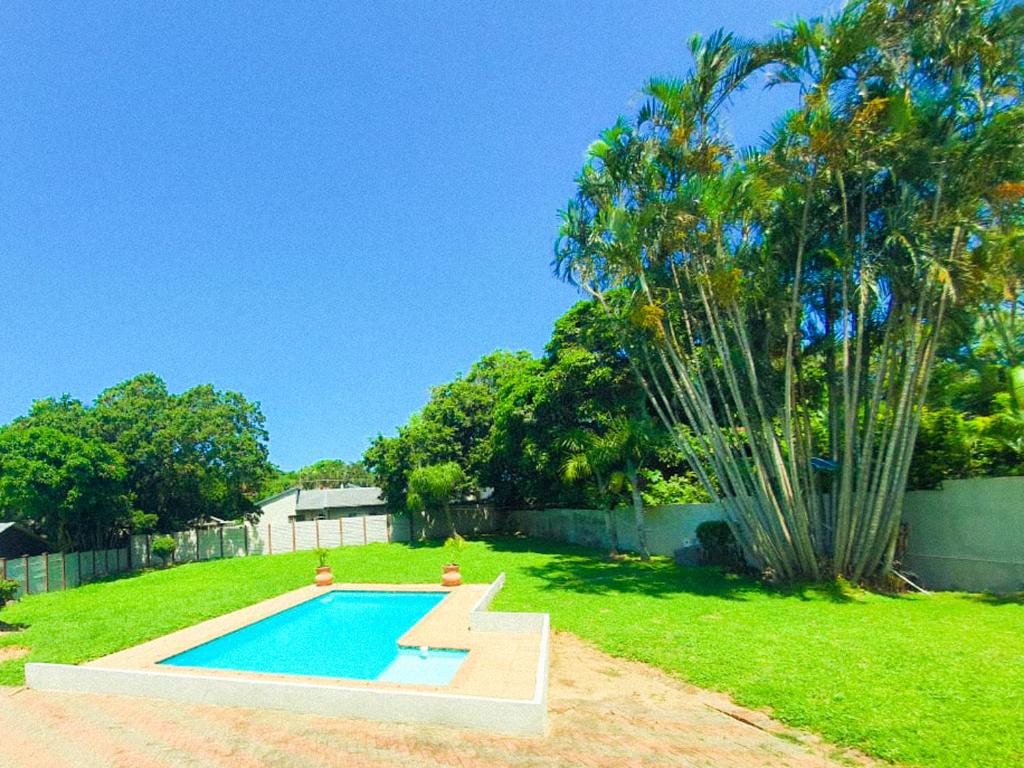 a swimming pool in a yard with a palm tree at Tranquil Coastal Home with Pool Family-Friendly Stay in Uvongo Beach