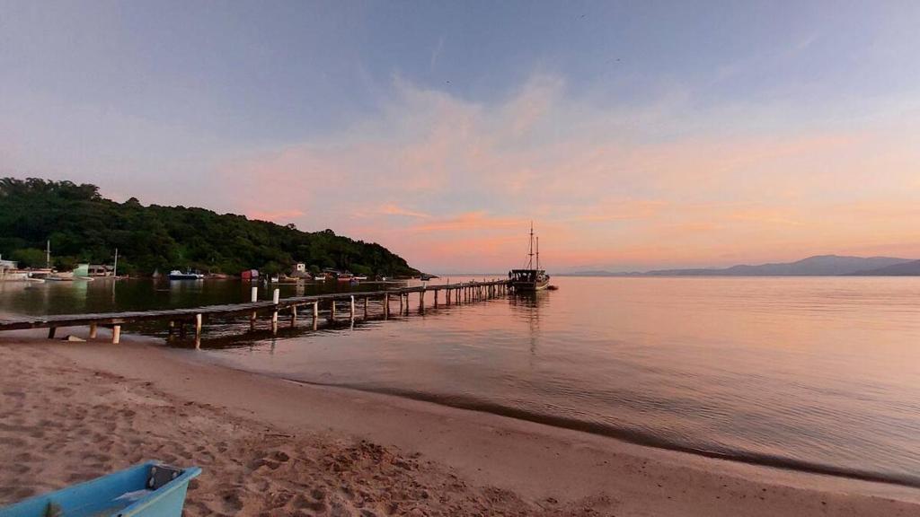 a dock on a beach with a boat in the water at Casa Governador Celso Ramos, praia Caieira do Norte in Governador Celso Ramos