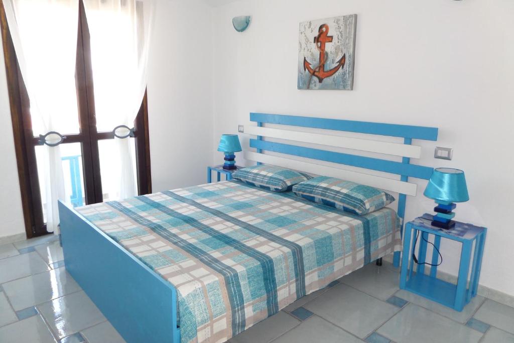 1 dormitorio con 1 cama azul y 2 lámparas azules en The Blue Lighthouse, en SantʼAntìoco