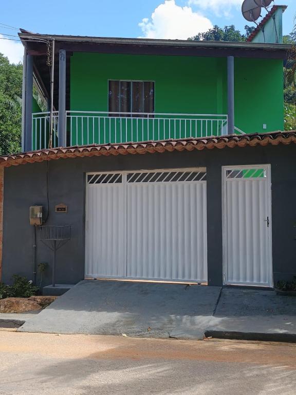 a green and white house with two white garage doors at Pouso AJH in Paraty