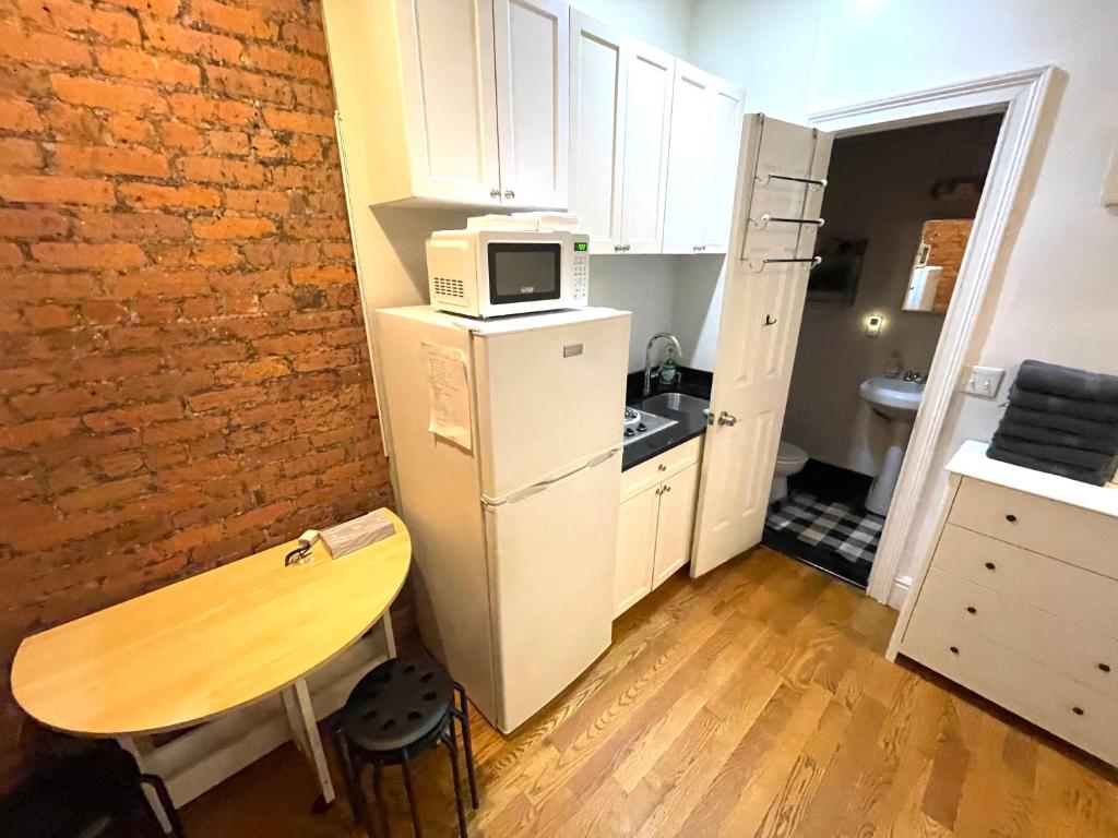 a kitchen with a table and a microwave on top of a refrigerator at Nestel Nest 1 bedroom apartment in New York