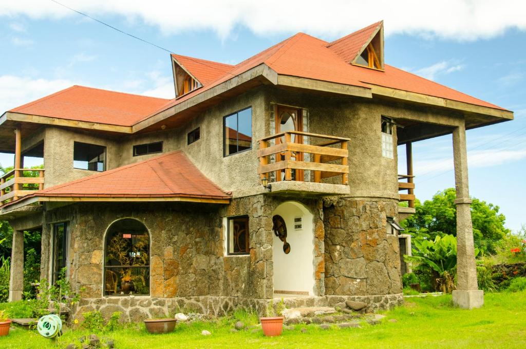 a house with an orange roof on a green field at Cabañas Moai in Hanga Roa