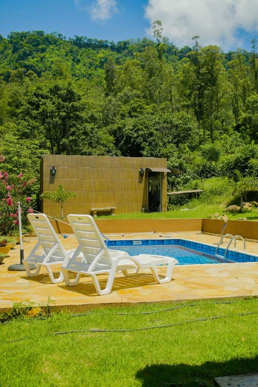 two chairs and a swimming pool in a yard at Chácara Itaqueri Safira in São Pedro