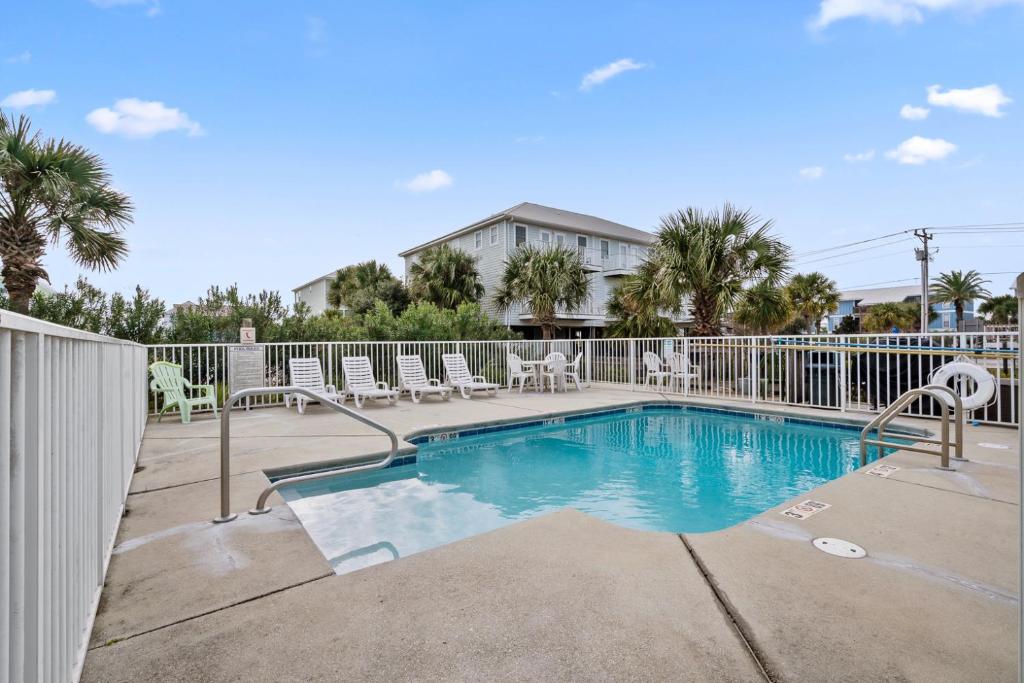 einen Pool mit Stühlen und einem Zaun in der Unterkunft Beautiful Two Bedroom, Two Bathroom First Floor Condo in Gulf Shores! in Gulf Shores