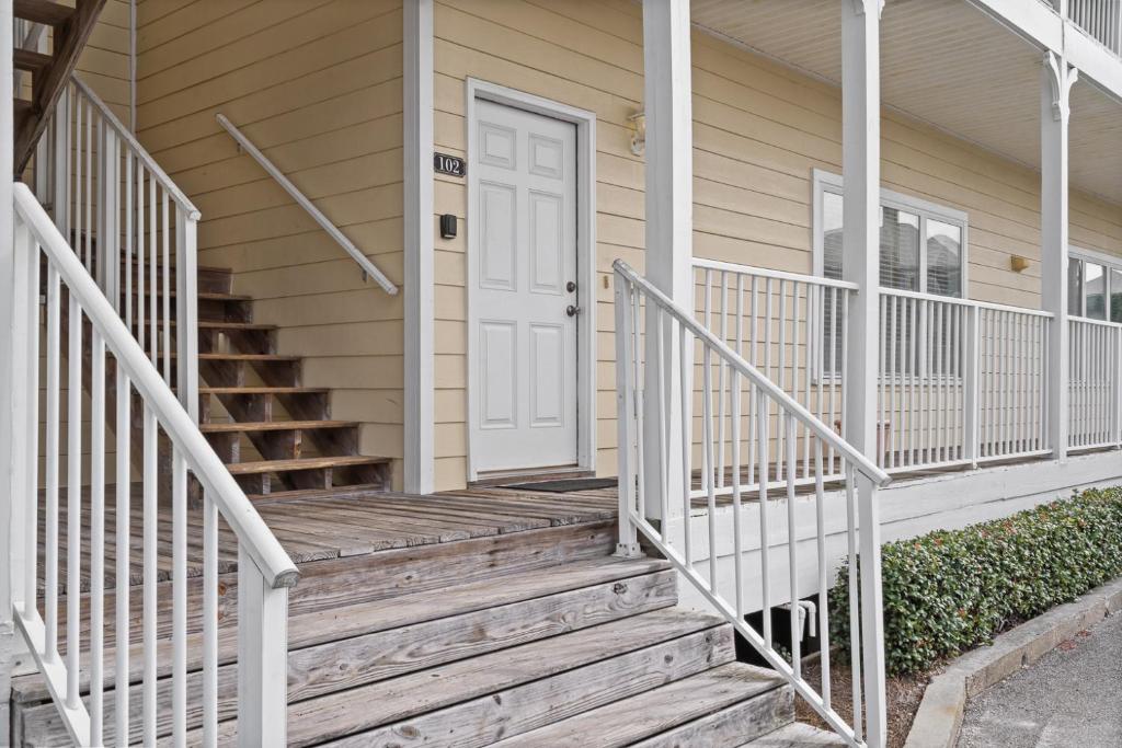 ein Haus mit einer Holztreppe, die zu einer weißen Tür führt in der Unterkunft Beautiful Two Bedroom, Two Bathroom First Floor Condo in Gulf Shores! in Gulf Shores