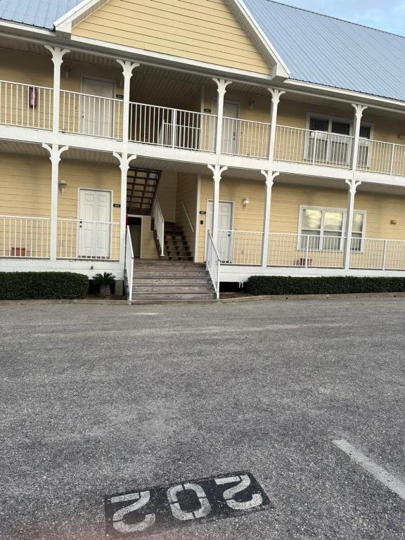 ein großes gelbes Gebäude mit einer Treppe und einer Veranda in der Unterkunft Beautiful Two Bedroom, Two Bathroom First Floor Condo in Gulf Shores! in Gulf Shores