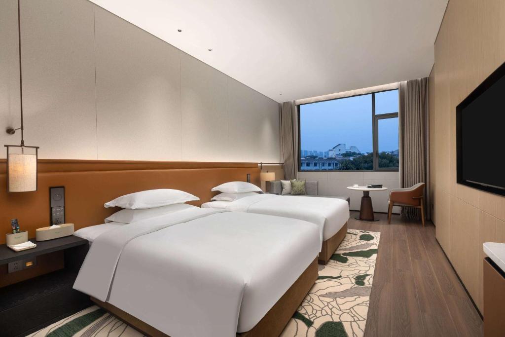 a hotel room with two beds and a flat screen tv at Wyndham Garden Xiangyang Xiangzhou in Xiangyang