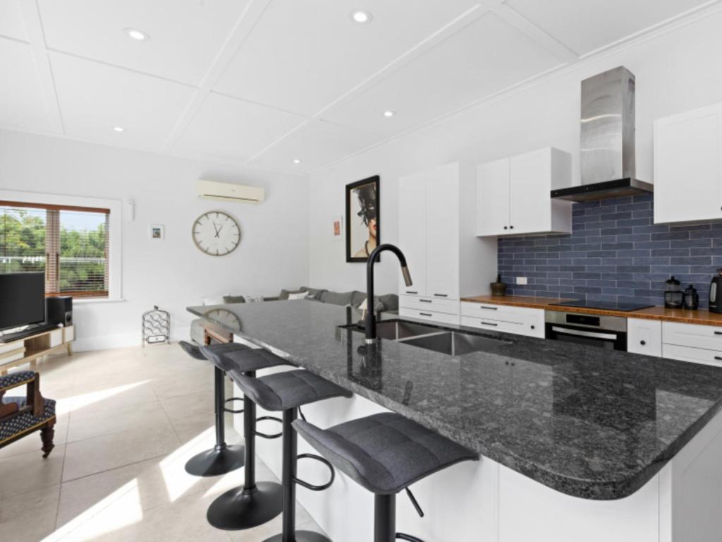 a kitchen with a large black counter top and chairs at Beautiful villa in Napier with spa in Napier
