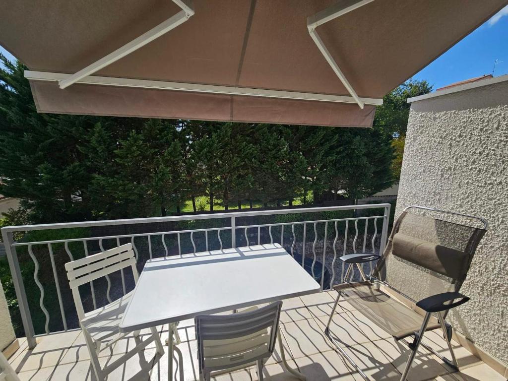 une table et des chaises sur un balcon avec un parasol dans l'établissement Appartement 4 pers à Royan avec balcon et parking proche plage du Chay - FR-1-550-89, à Royan