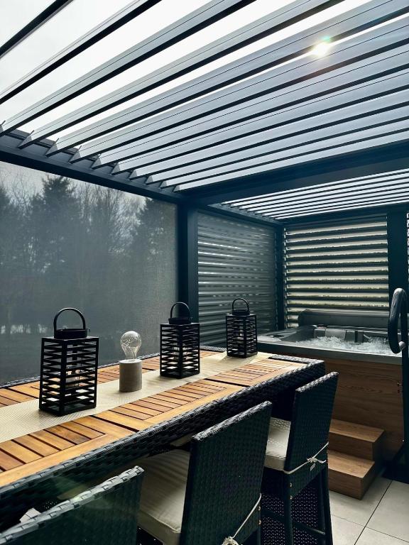 un patio avec une table et des chaises et un bain à remous dans l'établissement Villa BHD-Lodge & Spa, la tentation du luxe, à Blandouet