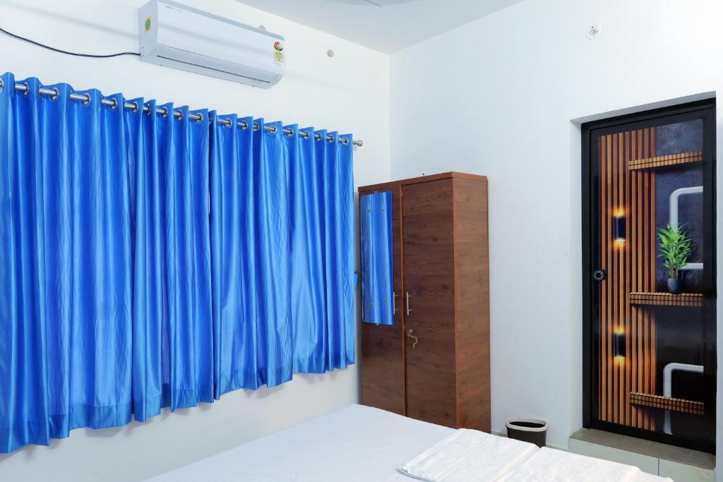 AlleppeySreeragam residency cherthala的一间卧室配有蓝色窗帘和窗户