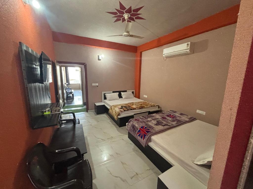 Una pequeña habitación con dos camas y un televisor. en Hotel Chandar Palace - Near Khatu Shyam Ji Temple, en Khātu