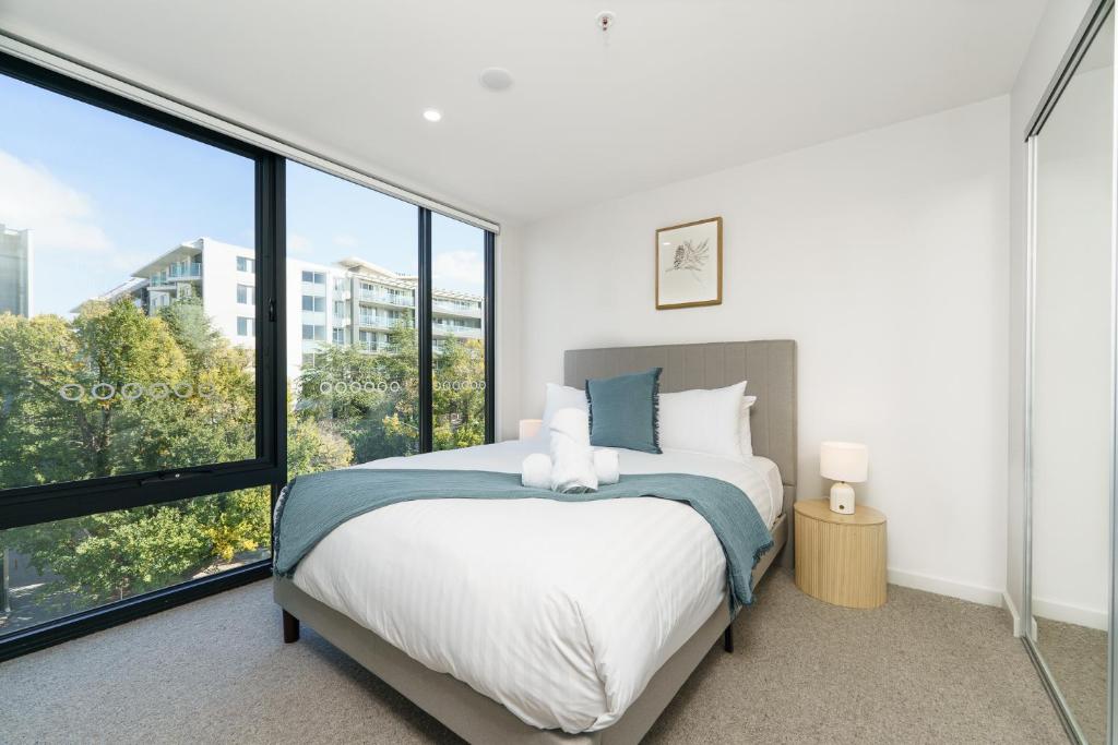 Un dormitorio con una cama y grandes ventanales. en Sleek Braddon Apartment Near Canberra Centre - Hosted by Canstay, en Braddon