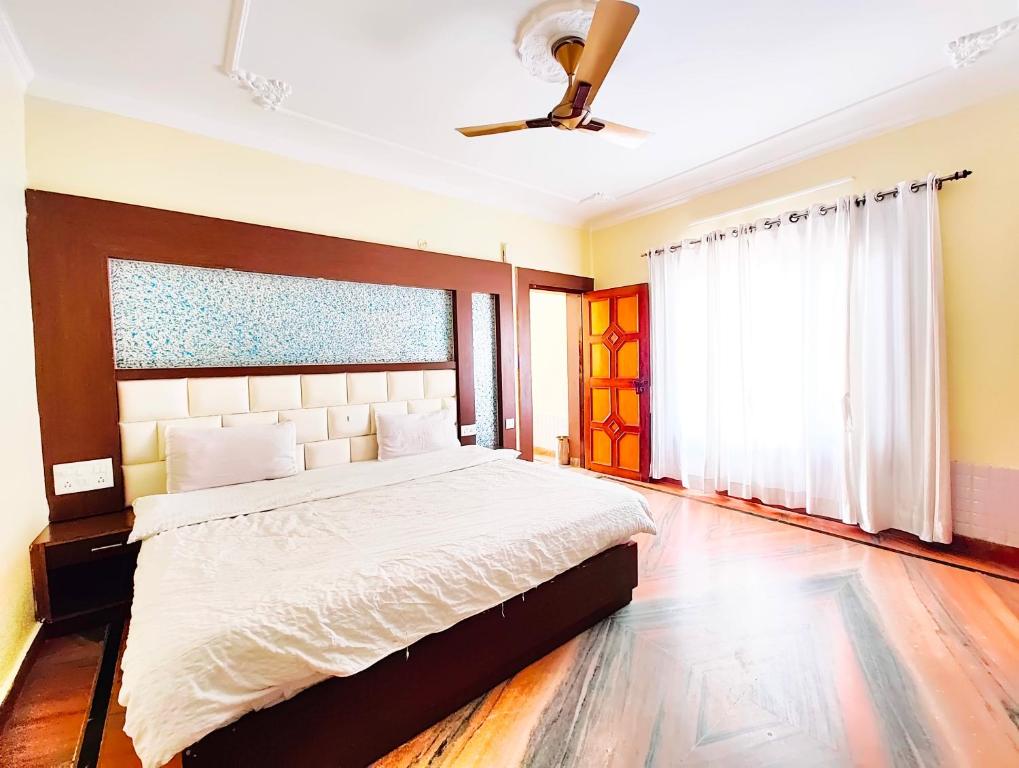 比姆塔尔A Premium Hotel Kavyansh Near Bypass Road - Hygiene & Spacious Room - BEST HOTEL IN BHIMTAL的一间带大床和吊扇的卧室