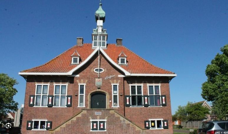 a large brick building with a clock tower on top at Herberg de Griffioen in Wolphaartsdijk