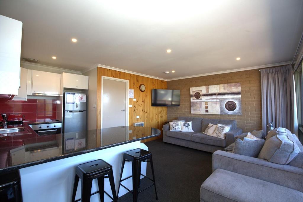 a kitchen and a living room with a couch and a table at Snowy Saga 1 46 Gippsland Street in Jindabyne