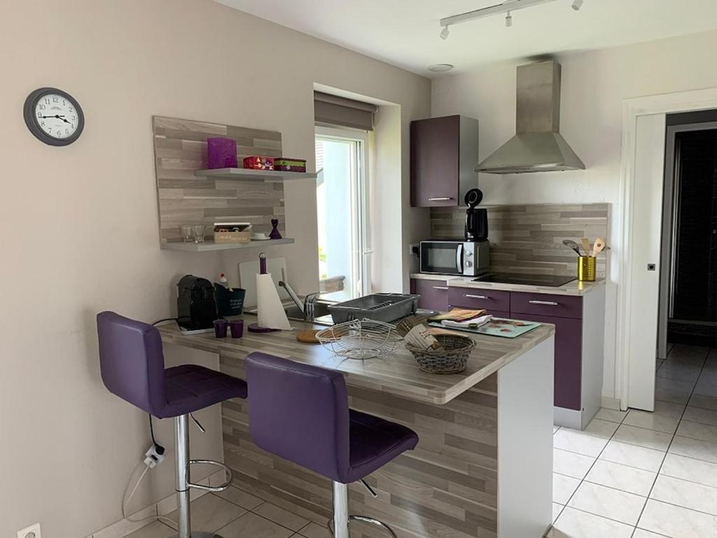 a kitchen with a table and two purple chairs at Le Prune, T2 proche plage de Morgat in Crozon