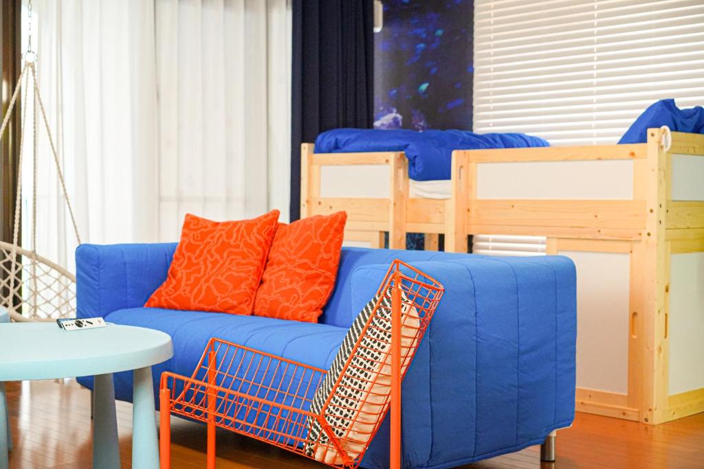 un divano blu con cuscini arancioni accanto a un letto di 150平米の丸々貸切のお部屋で国際通りまで徒歩圏内の最大宿泊14名可能 a Naha
