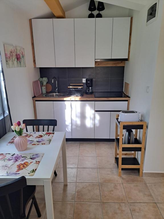 a kitchen with white cabinets and a table and a table and chairs at Sweet home in Rab
